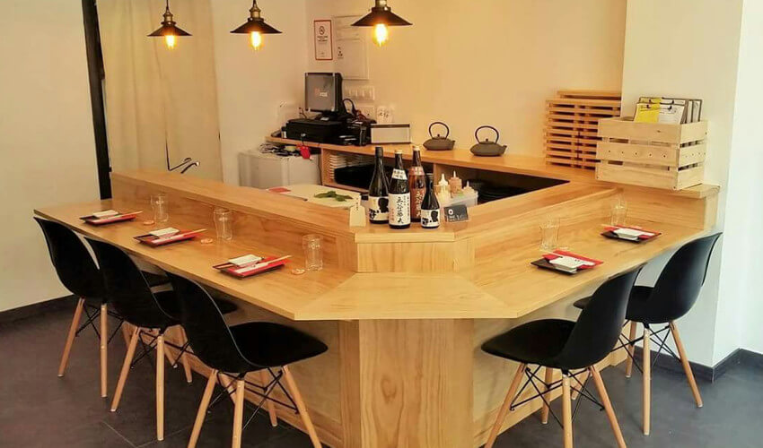Sillas réplica eames en color negro junto a barra en restaurante japonés Mobiliario para hostelería en Genji Sushi Bar